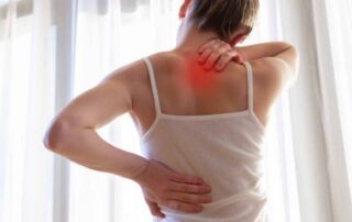 Why is my upper back so tight? Woman holding her upper back and neck while experiencing muscle tightness and pain.