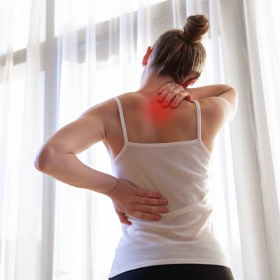 Why is my upper back so tight? Woman holding her upper back and neck while experiencing muscle tightness and pain.